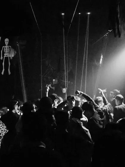 A wider black and white shot of the Insomnia Club, showing the scale of the crowd and the dramatic single-source lighting.