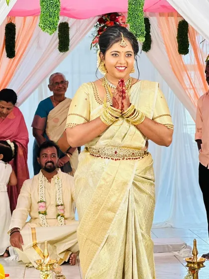 A candid shot of the bride during her wedding ceremony. She is wearing a classic off-white saree, and her makeup is kept natural and glowing.
