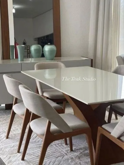 A clean and contemporary dining set with a white tabletop and a stylish wooden cross-base. The light grey upholstered chairs with their simple lines complement the table perfectly for a minimalist yet warm aesthetic.