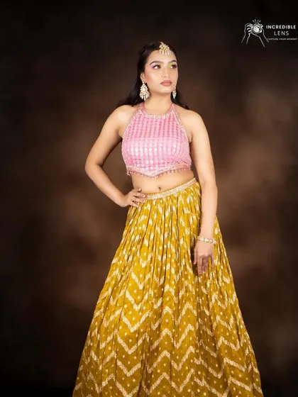 A full-length view of the colorful makeup look, paired with a yellow bandhani skirt and a pink halter top.