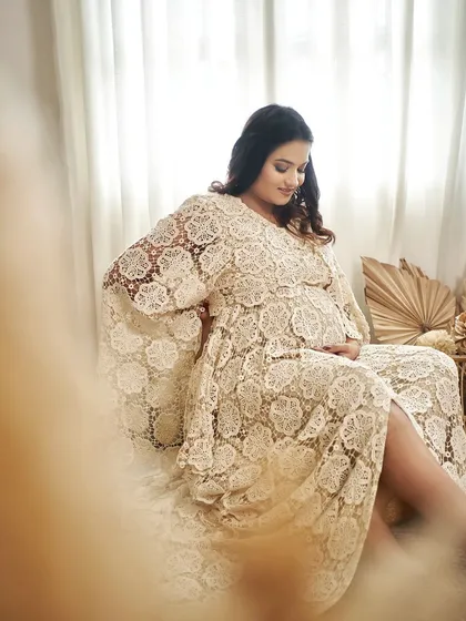 A beautiful, soft-focus shot of our Juene gown. The delicate lace fabric and relaxed fit are perfect for a comfortable and stylish maternity shoot.