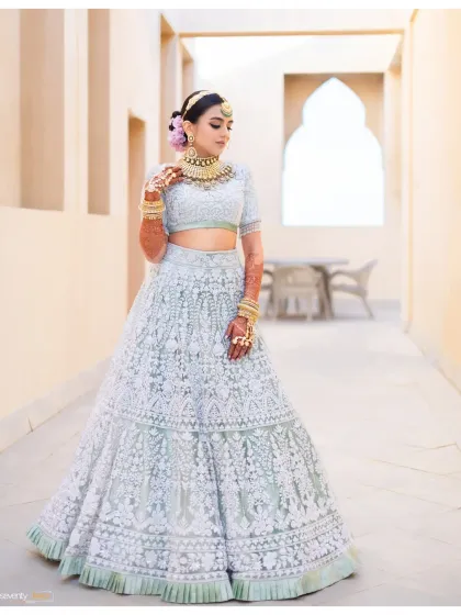 A bride stands in a serene corridor of the Waldorf Astoria in Dubai, her intricate lehenga a work of art against the clean, arched architecture of the luxury resort.