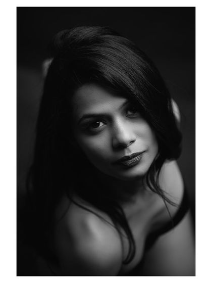 A close-up black and white portrait with a focus on emotion. The model's direct gaze is powerful and engaging.
