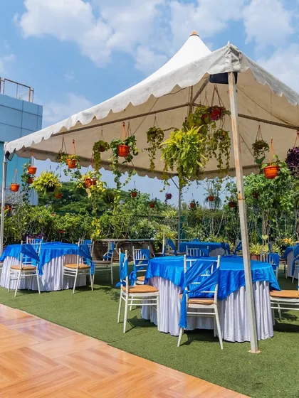 A daytime setup in the Terrace Garden, featuring a tent with hanging plants over a dining area, perfect for a brunch or lunch event.