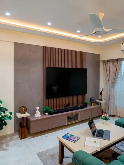 A view of the living room highlighting the TV unit with its combination of stone-finish laminate and wooden fluted panels.