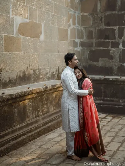 A quiet embrace against a historic stone wall. This photo captures a moment of comfort and togetherness, with the warm, earthy tones of the setting complementing the couple's traditional outfits.