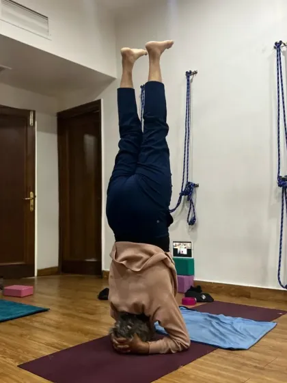 A student holding a steady Sirsasana (headstand) in the studio. Inversions are fantastic for building upper body strength and focus.