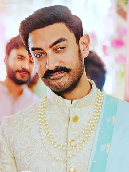 A close-up of the celebrity look you can get. This is Aamir Khan wearing an elegant cream sherwani with a pearl necklace and a light blue stole. I can help you recreate this entire ensemble.