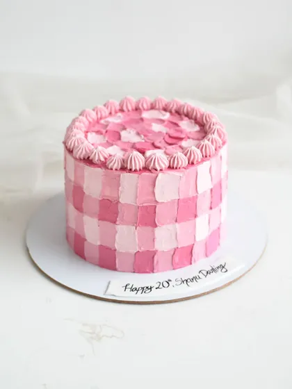 Pretty in pink! This cake features a modern take on a classic pattern with a checkerboard design created using a palette knife. The shades of pink and piped border give it a fun, retro feel.