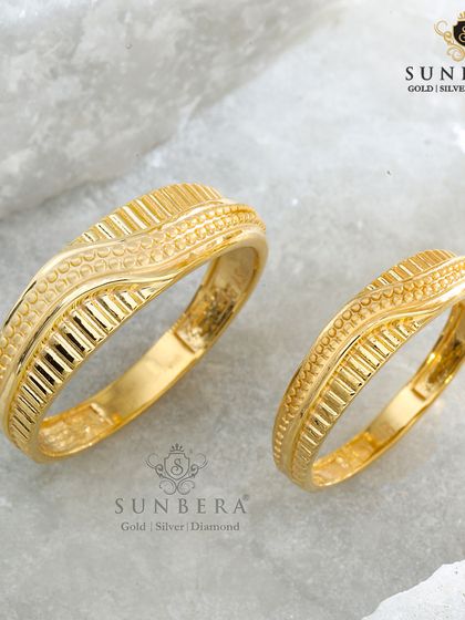 For those who appreciate texture and detail, these matching gold bands feature an intricate, wavy pattern. The design is crafted without stones, allowing the beauty and artistry of the goldwork to take center stage.