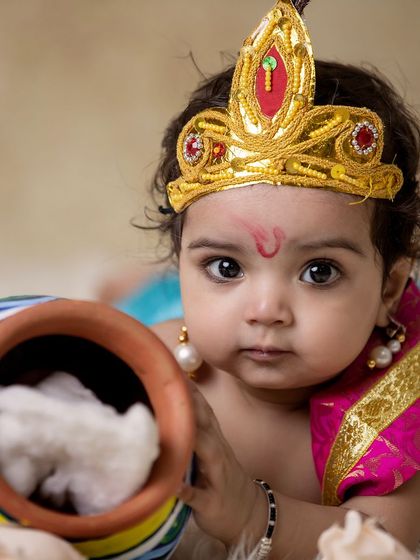 A striking close-up of a baby Krishna with a pot of 'butter'. His direct gaze and the traditional tilak on his forehead make this a powerful portrait.