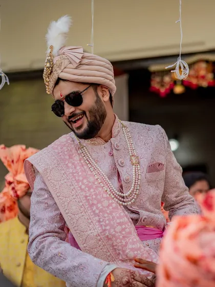 A candid shot of the groom, Nayan, smiling during his baraat. His sunglasses and joyful expression perfectly capture the fun and excitement of the moment.
