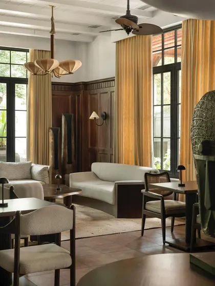Another view of the lounge, highlighting the custom, fan-like chandeliers and the soft, warm light filtering through the tall windows.