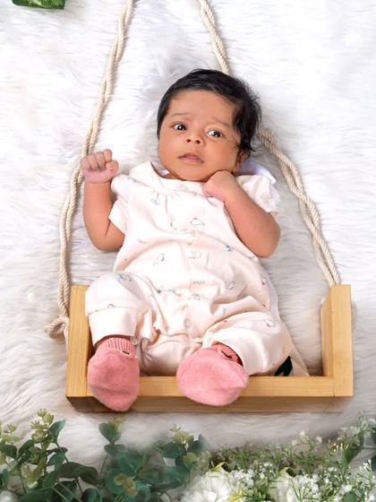 This little one is wide awake and curious, sitting on a miniature swing. It's a great example of how we capture both sleeping and awake moments during a newborn session.