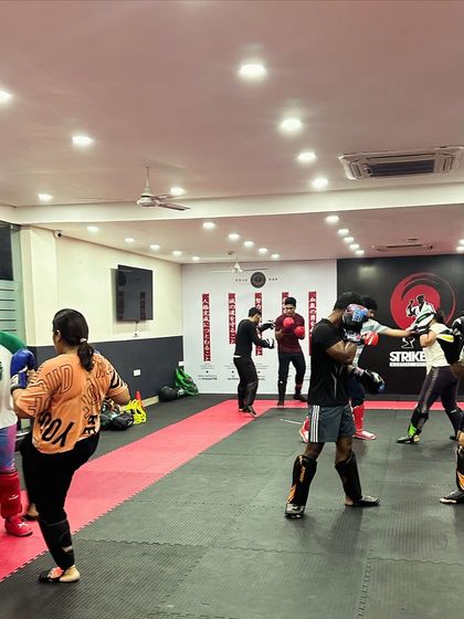 A wide view of an evening class engaged in various striking drills. Some students are sparring while others work on techniques, showing the dynamic nature of our training sessions.