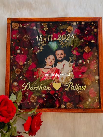 This varmala preservation frame is designed to be a centerpiece of love. The rich red flowers, combined with golden accents and a classic wooden frame, make it a truly special wedding memento.