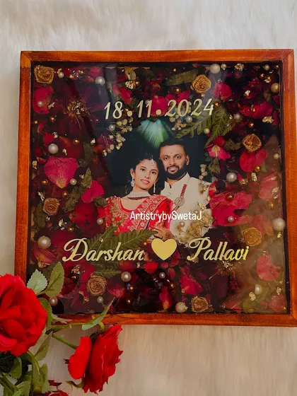 This varmala preservation frame is designed to be a centerpiece of love. The rich red flowers, combined with golden accents and a classic wooden frame, make it a truly special wedding memento.