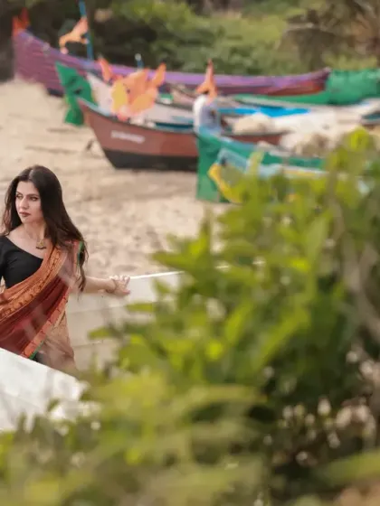 A serene moment captured at a fishing village, with the colorful boats in the background adding a touch of local flavor to the portrait.