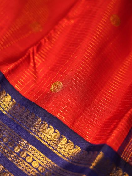 The fine gold checks on the red body of the saree add a subtle shimmer and texture to the overall drape.