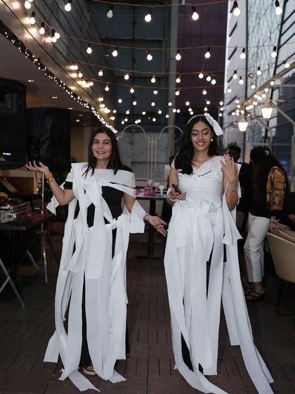 Two teams showing off their creative toilet paper wedding dress designs.