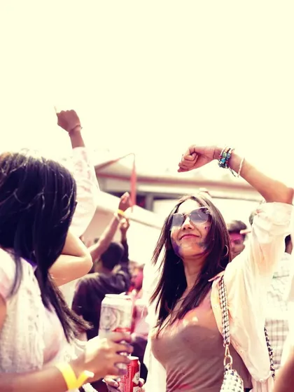 A partygoer enjoying a drink and the music at the Holi festival, embodying the relaxed and fun atmosphere of the event.