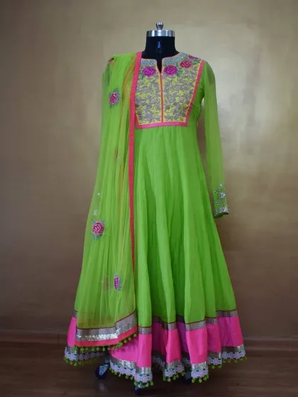 For a vibrant and festive look, I created this neon green Anarkali suit. It features detailed floral threadwork and mirror work on the yoke, with a matching pink border and playful tassels, making it perfect for a wedding sangeet or festive celebration.