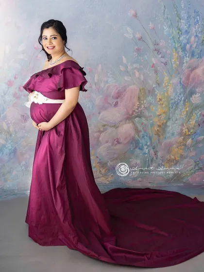 A portrait of pure elegance. The rich magenta gown with its long train creates a dramatic and luxurious feel against the soft, painted backdrop.