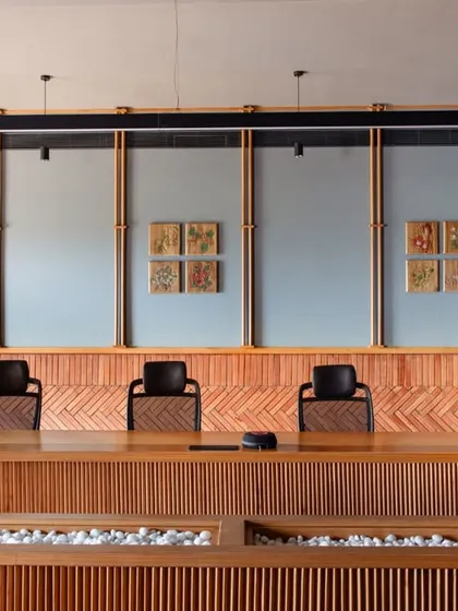 The boardroom at Anthea Pharma was designed with acoustics as a primary focus. We used a combination of brick cladding in a herringbone pattern and custom acoustic panels framed by teakwood spindles to create a space that is both sonically optimized and visually warm, perfect for high-level corporate discussions.
