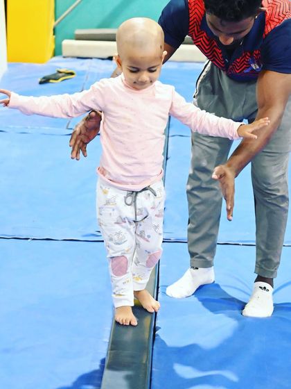 Finding her balance. With a coach's steady hand for support, this young gymnast learns to walk on the beam, a foundational skill for artistic gymnastics.