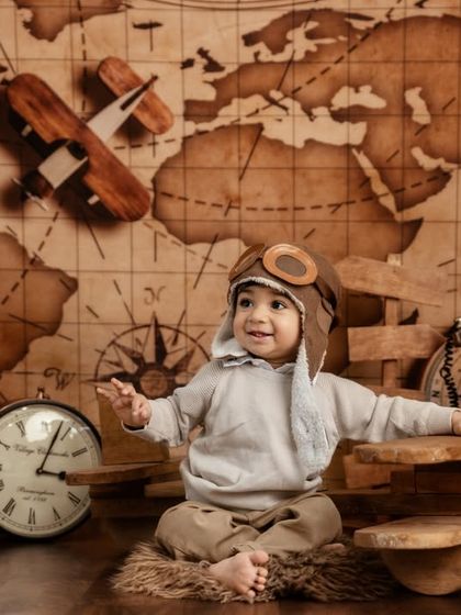 Dressed in a classic aviator hat and goggles, this little explorer is full of excitement for his first birthday adventure.