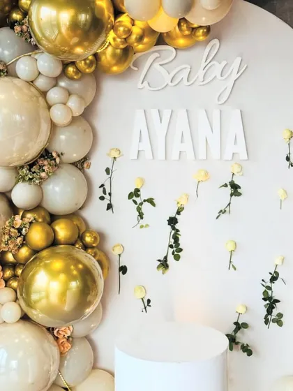 A close-up of the backdrop, showing the 'Baby Ayana' name sign and the delicate wall of white roses.