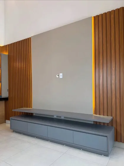 An unfinished TV unit structure, showing the wooden fluted panels and the space for the central panel and console. This gives a glimpse into the construction process before the final finishes are applied.