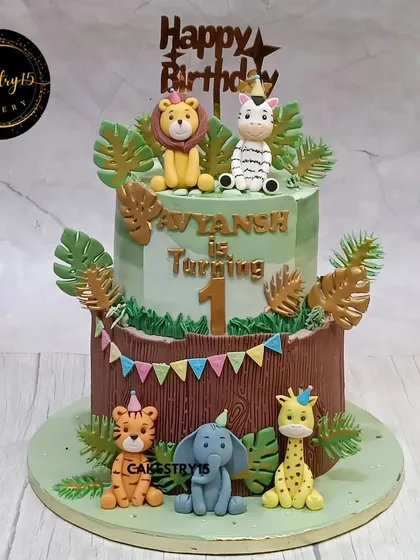 A vibrant two-tier jungle safari cake for a first birthday. This 5kg chocolate cake features a host of handcrafted fondant animals, including a lion, zebra, tiger, elephant, and giraffe.