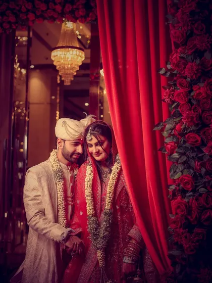 A quiet, stolen moment between the couple, framed by dramatic red curtains, creating a sense of intimacy.