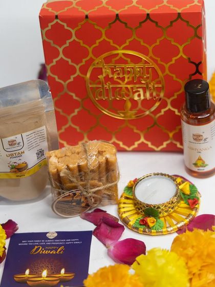 This beautifully arranged Diwali gift set includes a stack of my handmade Ubtan soaps, a pouch of Ubtan powder, Abhyanga oil, and a traditional diya, all packed in a festive red box.