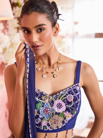 A beauty close-up from the festive campaign, highlighting the detailed floral embroidery on the blouse. The makeup is soft and luminous, with a focus on flawless skin and a subtle shimmer.