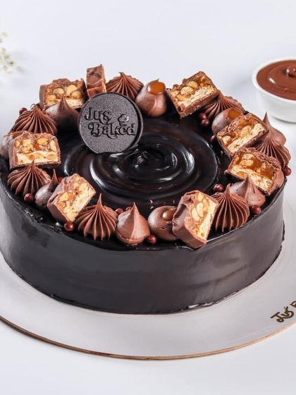 This rich chocolate cake is topped with chunks of Snickers, caramel, and chocolate swirls. It's a decadent treat that satisfies any chocolate and caramel craving.