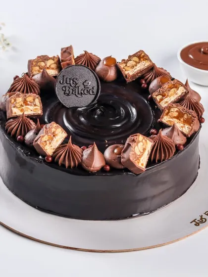 This rich chocolate cake is topped with chunks of Snickers, caramel, and chocolate swirls. It's a decadent treat that satisfies any chocolate and caramel craving.