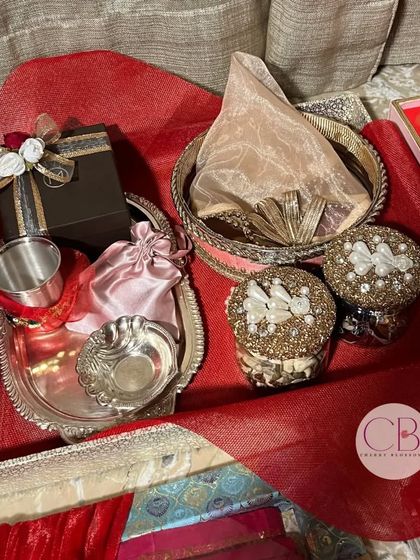 A Karwa Chauth special sargi hamper with trousseau packaging. This beautiful set includes a silver thali, decorative sieve, and beaded boxes, all elegantly arranged.