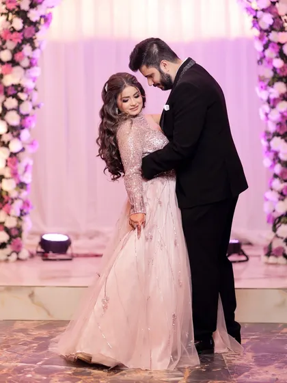 A classic romantic pose from an engagement shoot. The couple is framed by a beautiful floral arch, and the soft lighting creates a dreamy atmosphere.
