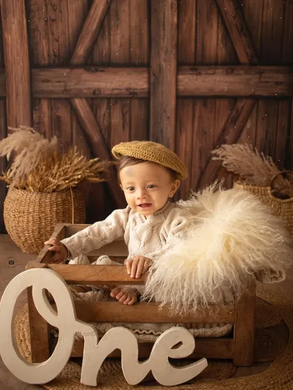 This little boy, dressed in a cozy sweater and beret, smiles from a wooden crate next to a "One" sign.