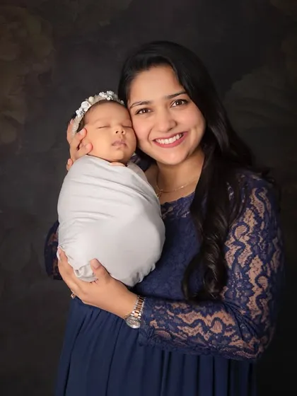 A glowing new mother holding her peacefully sleeping newborn. The simple swaddle and dark backdrop put all the focus on the beautiful bond between mother and child.