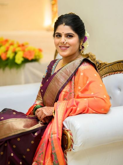 The bride Shalmali seated, looking serene and beautiful. Her makeup is soft and subtle, perfect for a traditional daytime wedding ceremony.
