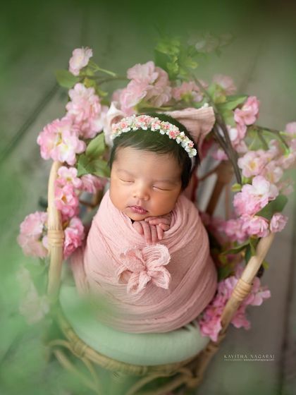 A nine-day-old newborn girl, wrapped like a present in a pink bow and surrounded by cherry blossoms. A beautiful, artistic celebration of new life.