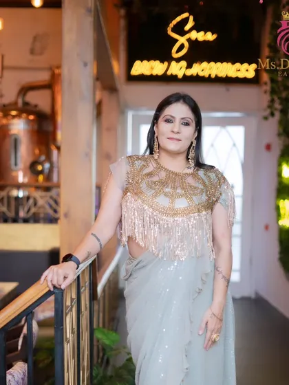 An outfit photoshoot with a model in a gorgeous fringed blouse and saree. The makeup is designed to complement the high-fashion look.