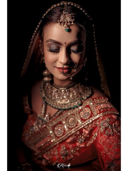 A dramatic, low-light portrait of a bride, focusing on her intricate makeup and jewelry.