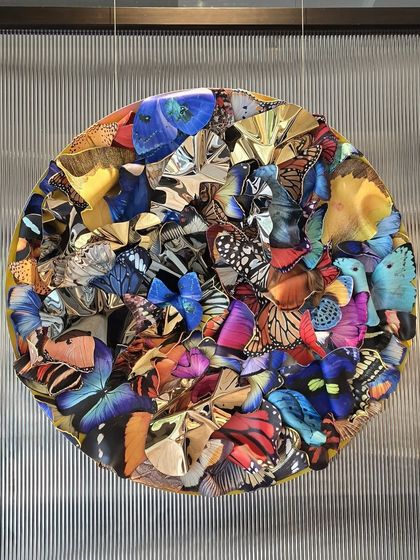 "Metamorphosis in Metal," a circular installation where a vortex of colorful butterflies surrounds a core of crumpled, reflective steel.