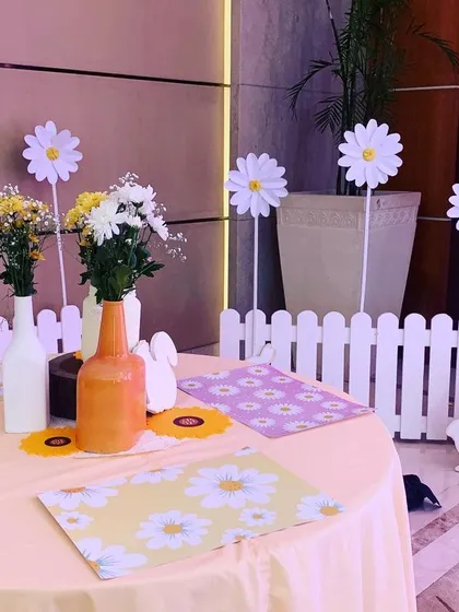 A table setting at the Daisy party, with daisy-print placemats, simple flower arrangements, and a charming white picket fence detail.