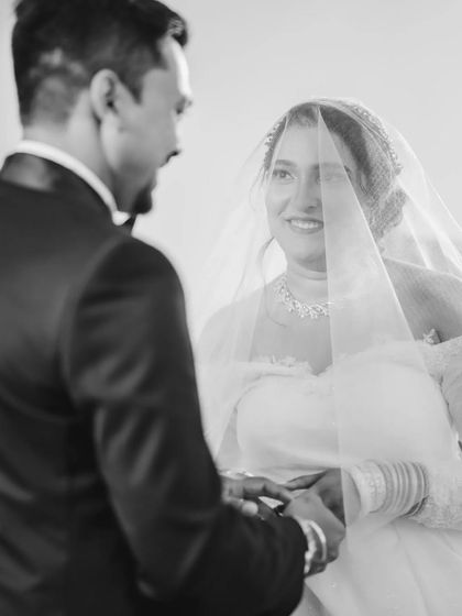 The bride's emotional gaze at her groom during the ring exchange, captured in timeless black and white. The veil softens the image, adding to the romance.