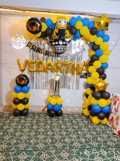 A Minions-themed first birthday party with a yellow, blue, and black balloon arch and character foils.
